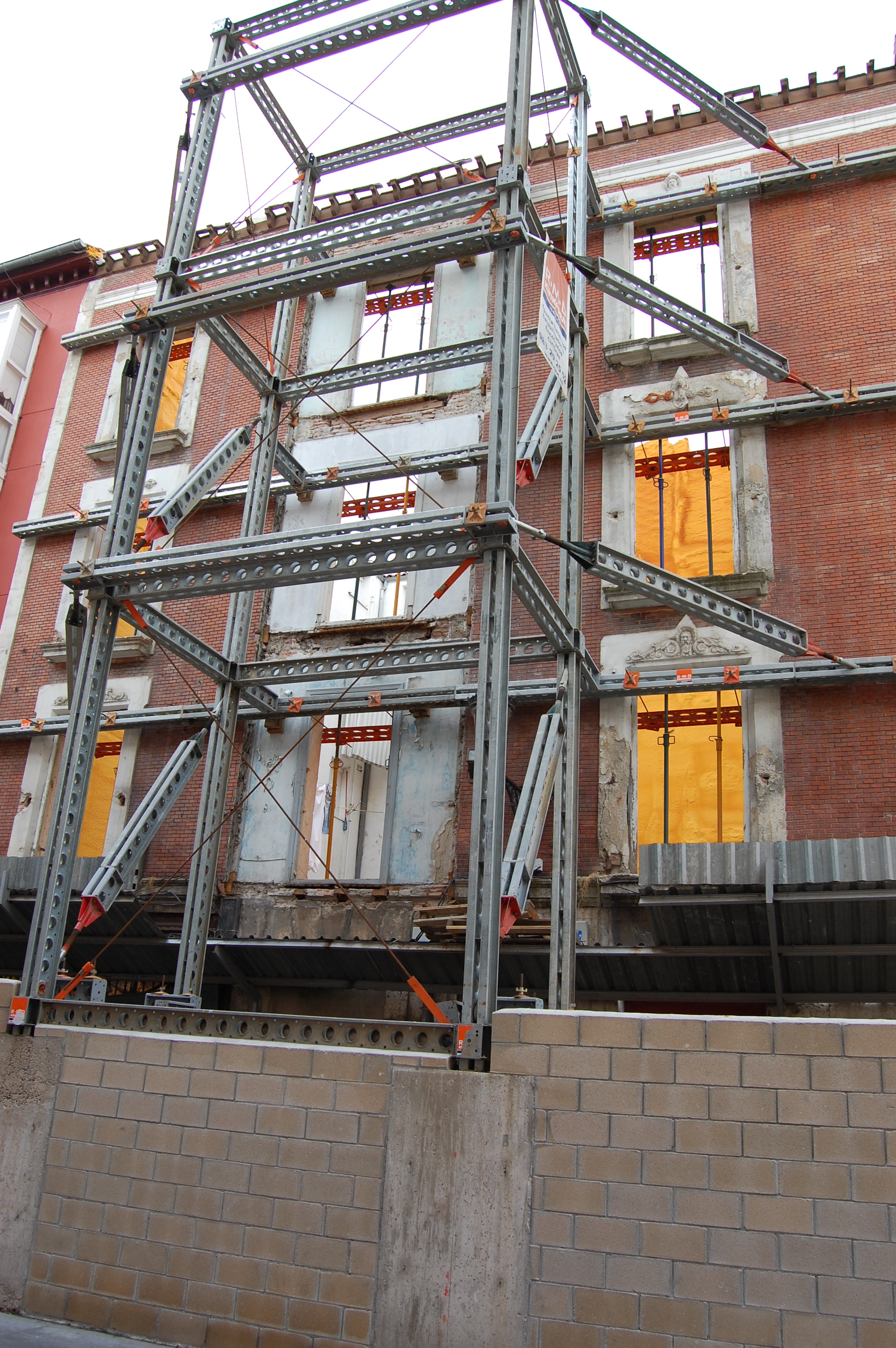 Foto de una facha de un edificio que se ha vaciado apuntalada mediante una estructura metálica auxiliar.